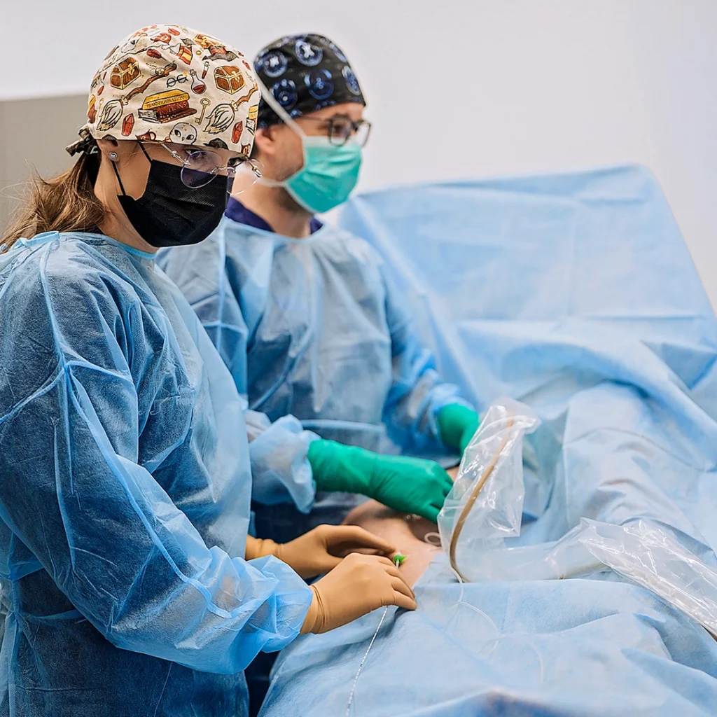 Procedura laserowa ELVeS 1470 nm 1940 nm zamykania żylaków - zespół flebologów w sterylnym stroju podczas miniinwazyjnego zabiegu endowaskularnego - Klinika Flebologii
