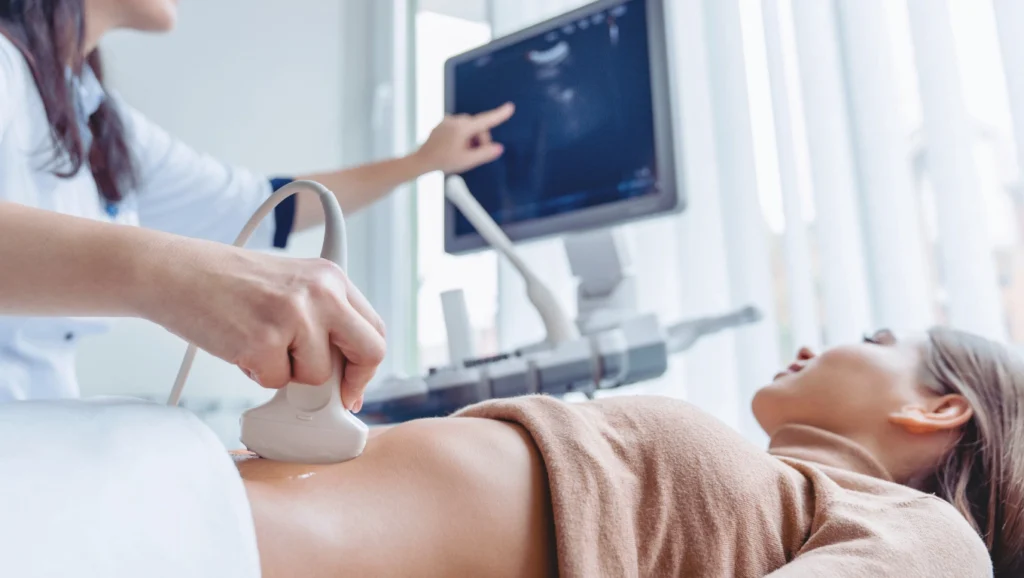 Młoda kobieta ma wykonywane badanie USG Doppler żył miednicy przed zabiegiem embolizacji żylnej w Klinice Flebologii.